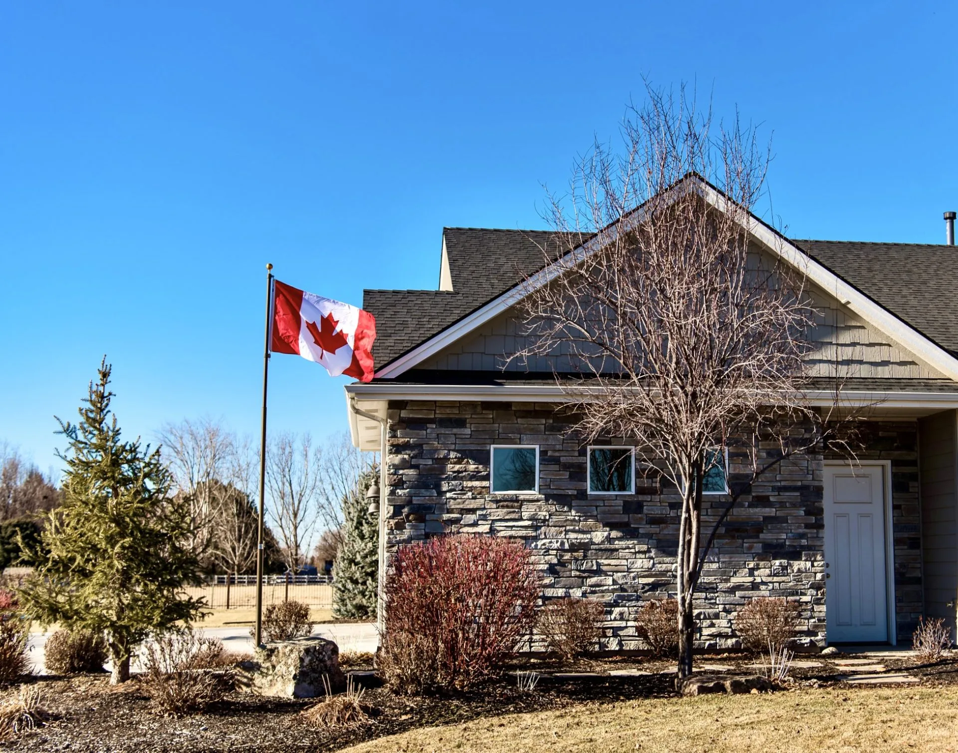 A flagpole provided by The Flag Shop outside a house flying the Canadian flag.