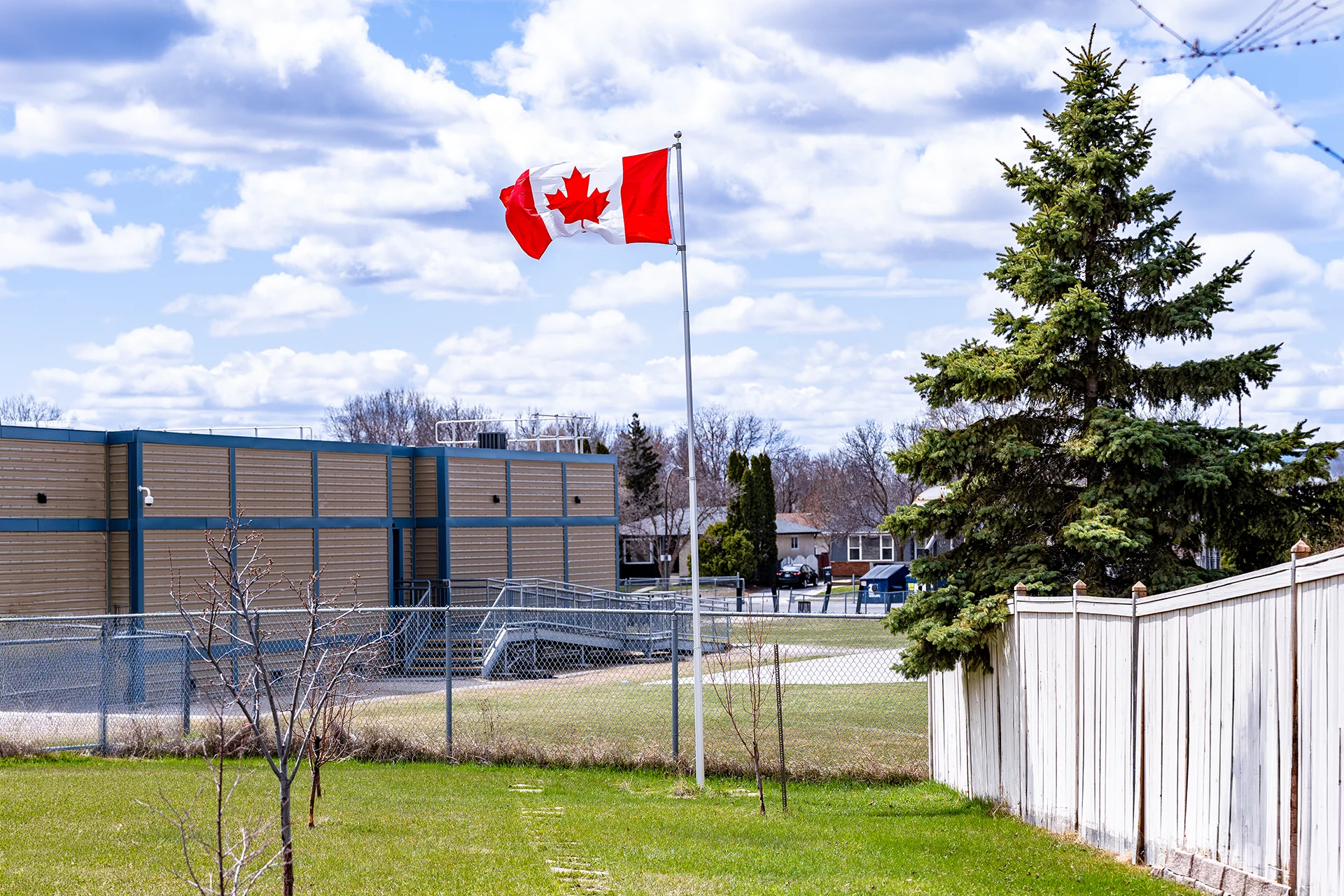 A Titan telescoping flagpole with a silver anodized finish outside of a school flying a Canadian flag.